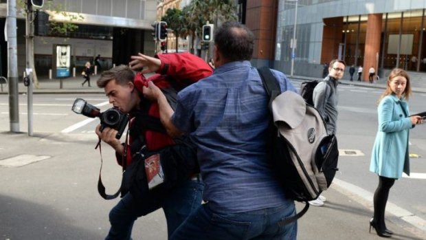 Waiting in the wings: Bruce Wilson attacks a photographer outside the hearing.