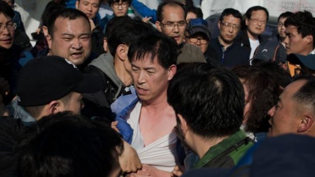 Angry reception ... relatives of victims of the Sewol ferry confront deputy director of the South Korean coastguard Choi Sang-Hwan (centre) as they forcibly remove him from an office at Jindo harbour.