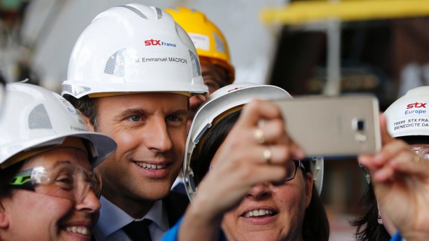 French President Emmanuel Macron poses for selfies as he visits the MSC Meraviglia cruise ship at the STX shipyard site in Saint-Nazaire, western France.
