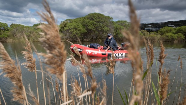 Police in an inflatable dinghy search the Paincalak Creek.