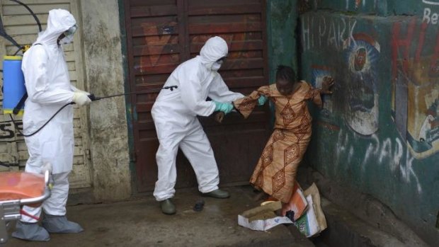 A woman suspected of being infected with Ebola is assisted by health workers to an ambulance for treatment in Freetown, Sierra Leone, during a national lockdown.