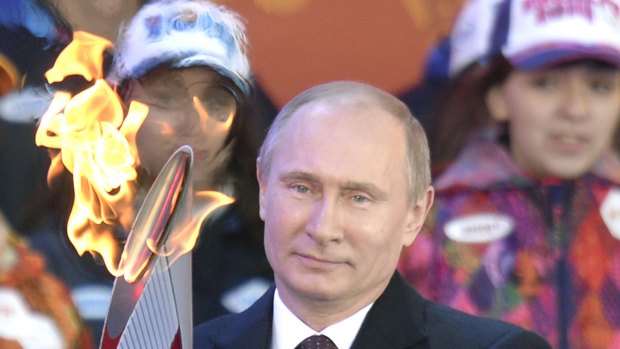 Russian President Vladimir Putin holds the Olympic flame in Moscow.