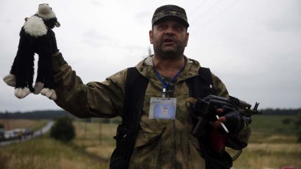 A pro-Russian separatist holds up a stuffed toy found at the crash site.