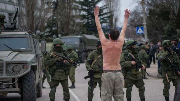 A Ukrainian man stands in protest in front of gunmen in unmarked uniforms as they stand guard in Balaklava, on the outskirts of Sevastopol, Ukraine.