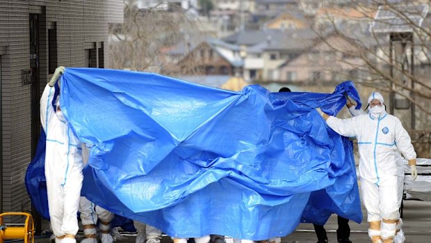 Workers who stepped into radiation-contaminated water at the Fukushima Dai-ichi nuclear plant are shielded with tarps before receiving decontamination treatment.