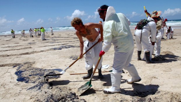 Workers clean up the oil that has spilled on to the coast of Moreton Island.