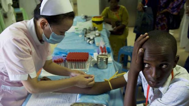 A Chinese nurse working onboard a hospital ship takes a blood sample from a Kenyan teenager in Mombasa.