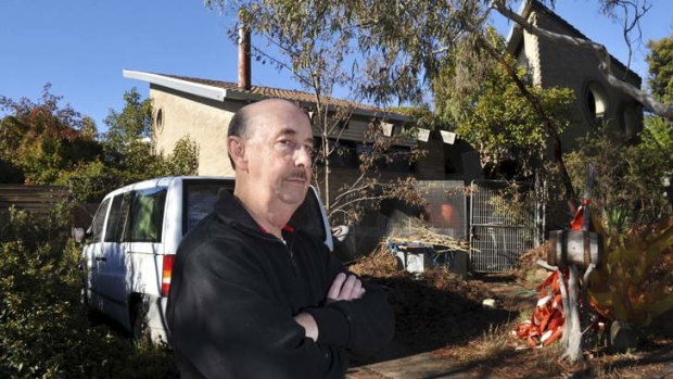 A neglected and unfinished home in Yambina Crescent, Warramanga, much to the ire of immediate neighbour, Wayne Mitchell, pictured in front of the house.