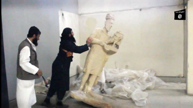 An IS jihadist pushes a statue over inside the Mosul museum in the northern Iraqi Governorate of Nineveh. 