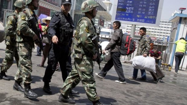 Armed Chinese paramilitary policemen march past the site of an explosion outside the Urumqi South Railway Station in Urumqi in northwest China in May.