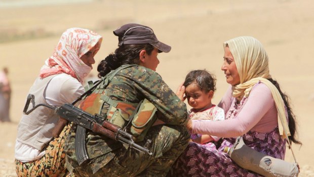Displaced people from the minority Yazidi sect get help from a member of the Kurdish People's Protection Units (YPG) as they make their way towards the Syrian border in August last year.