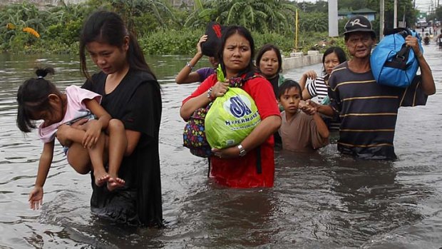 Residents wade in waist-deep floodwaters in order to get to their submerged shanties in Valenzuela, north of Manila .