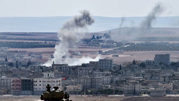 Kobane burns ... Turkish soldiers in a tank observe the Syrian town of Kobane  from a hill at the Turkish-Syrian border.