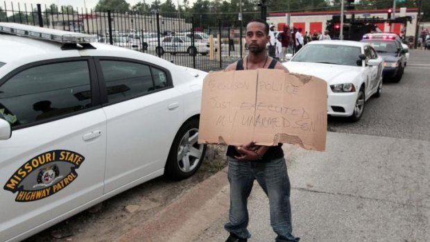 Louis Head, stepfather to 18-year-old Michael Brown who was fatally shot by police, holds a sign in Ferguson, Missouri, near St Louis on Saturday.
