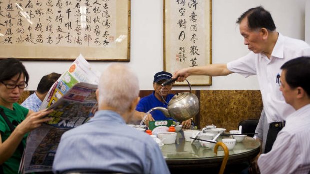 Atmospheric ... a waiter pouring tea for yum cha diners at Lin Heung Tea House in Hong Kong.