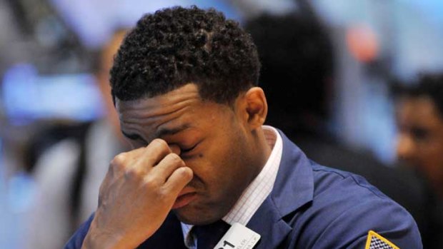 A trader bows his head on the floor of the New York Stock Exchange.