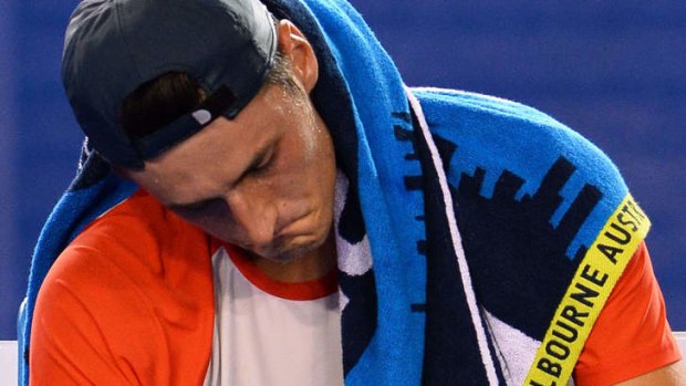 Bernard Tomic hangs his head after pulling out of his match with Rafael Nadal.