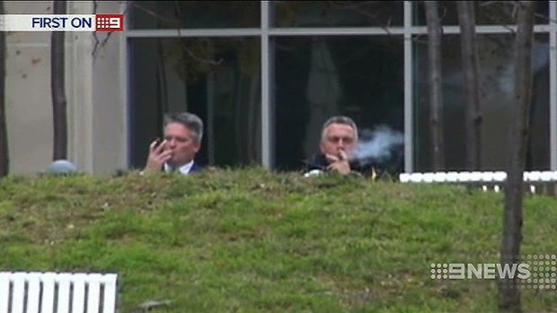 Mathias Cormann and Joe Hockey enjoy cigars outside the Treasury in Canberra. Photo: Nine News