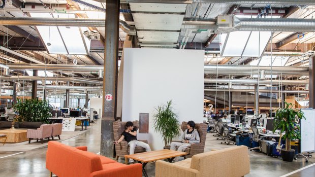 Employees huddle at one of the many casual meeting spaces inside Building 20.