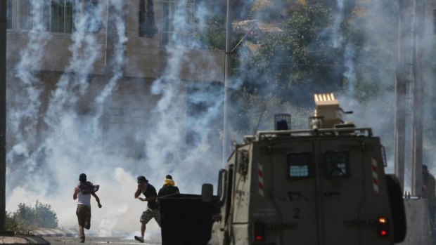Pro-hunger striker protesters run for cover during an Israeli tear-gas attack in the West Bank city of Ramallah.