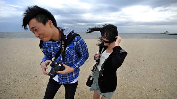 Winston Liu and Sally Li being blown about in the blustery winds at St Kilda beach.