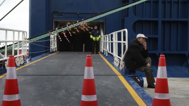 A man smokes at the entrance of an immobilised ferry at the Piraeus port near Athens.