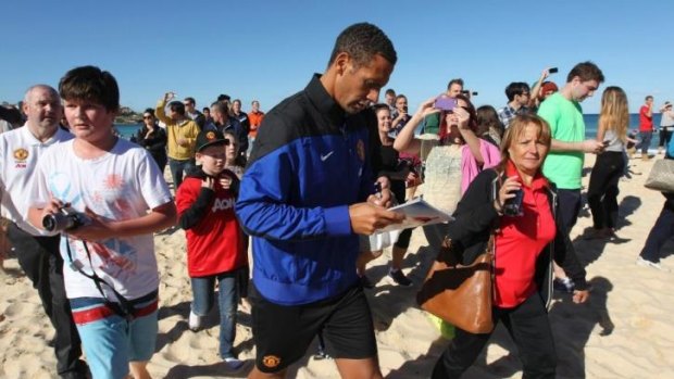 Manchester United defender Rio Ferdinand is mobbed by supporters on Bondi Beach in July.