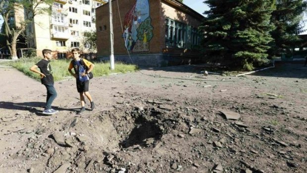 Boys stand near a shell crater outside a local school in the eastern Ukrainian town of Kramatorsk.