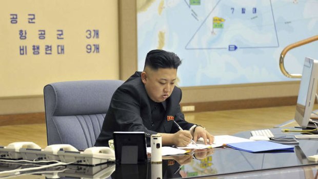 This photo taken and released by North Korea's official Korean Central News Agency (KCNA) on March 29, 2013 shows North Korean leader Kim Jong-Un looking at and signing documents at an undisclosed location, in front of a map which appears to show the tracked or projected movement of the US Seventh Fleet in the Pacific Ocean.