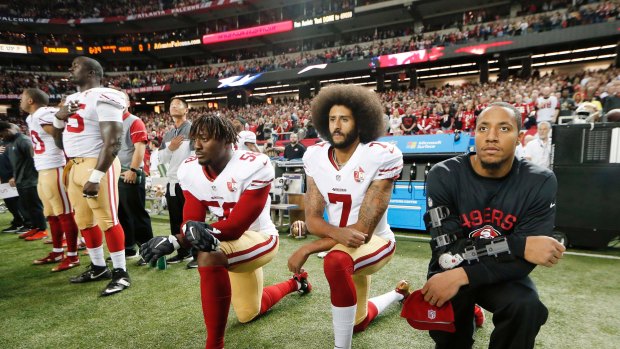 Former San Francisco 49ers quarterback Colin Kaepernick (centre) and teammates kneel during the playing of the US national anthem.