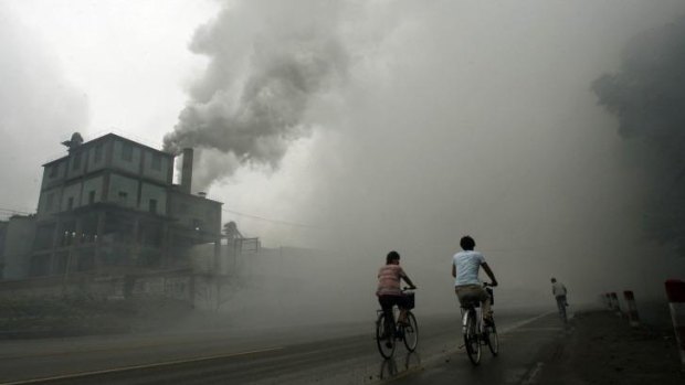 This 2006 file photo shows cyclists passing through thick pollution from a factory in Yutian, 100km east of Beijing, China. 