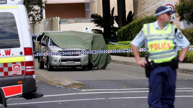 A tarpaulin covers a car linked to a fatal shooting outside the police station on Castle Street, Castle Hill.