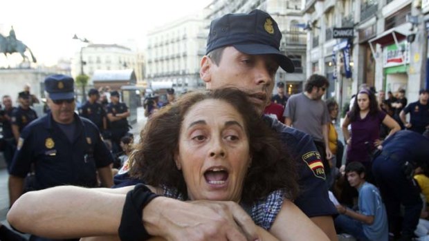 Pain in Spain ... a demonstrator is removed by police from Madrid's Puerta del Sol square as fear spreads about the state of the nation's economy.