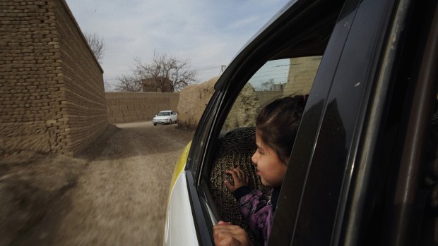 A young passenger looks out the back window of Sara Bahayi's taxi. 