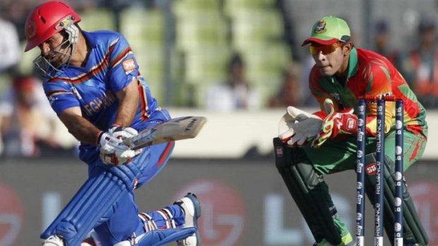 Afghanistan's captain Mohammad Nabi plays a sweep as Bangladesh's wicketkeeper Mushfiqur Rahim looks on.