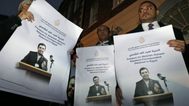 Demonstrators hold placards with pictures of Al-Jazeera Arabic network journalist Abdullah Al Shami who was detained along with cameraman Mohamed Badr.