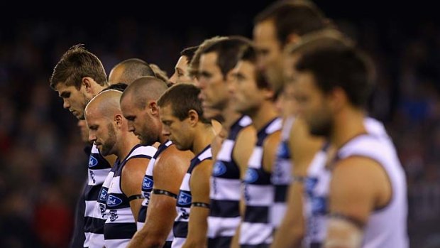 Reverential: Geelong players bow their heads in tribute to legendary Cat player and coach Bob Davis.