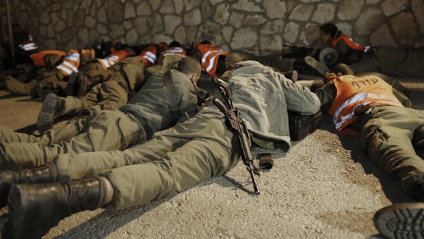 Israeli soldiers take cover as an air raid siren warns of incoming rockets before the funeral of Aaron Smadja, one of the three Israelis killed by a rocket fired from Gaza, in the southern town of Kiryat Malachi.