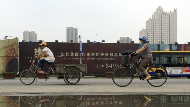 Cyclists ride past newly built residential housing in Beijing, China.