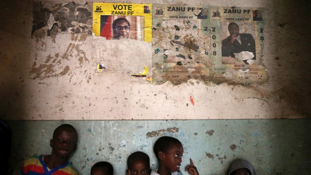 Children stand beneath posters from the 2008 Zanu Pf election campaign in the Mbara suburb of Harare on Friday November 17.
