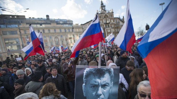 Demonstrators hold a portrait of slain opposition leader Boris Nemtsov and  Russian flags during a march marking the anniversary of his killing.