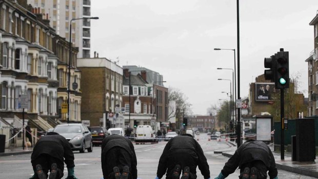 Police officers search a street for forensic evidence in Stockwell after the shootings.