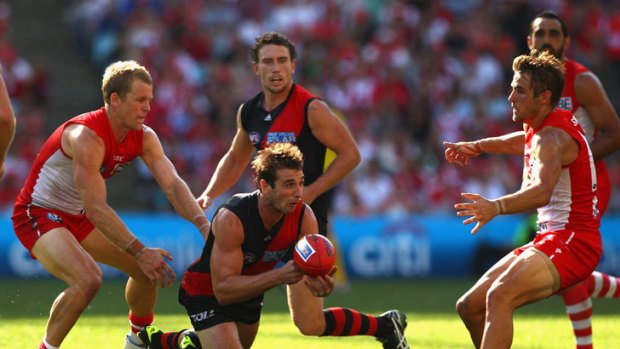 Under siege: Essendon captain Jobe Watson gets a handball away as Swan Ryan  O’Keefe (left) moves in to tackle.