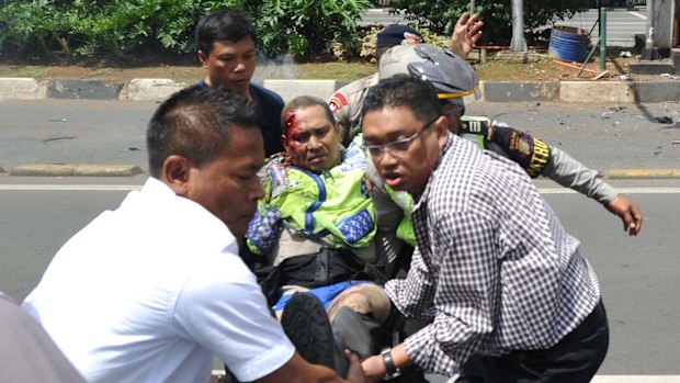 People carry an injured police officer near the site where an explosion went off at a police post in Jakarta.