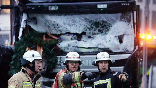 Fire fighters stand in front of a truck which ran into a crowded Christmas market killing several people Monday evening in Berlin, Germany, Tuesday, Dec. 20, 2016.(AP Photo/Markus Schreiber)