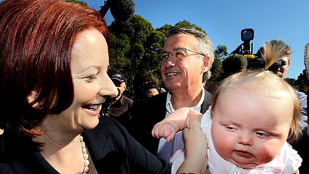 Babies beware, election campaign under way: Julia Gillard gives Charlotte McColl a hug as Wayne Swan looks on in Brisbane yesterday.