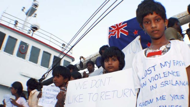 Take us to New Zealand ... Sri Lankan asylum seekers wave signs after Indonesian authorities intercepted their boat near Bintan Island.