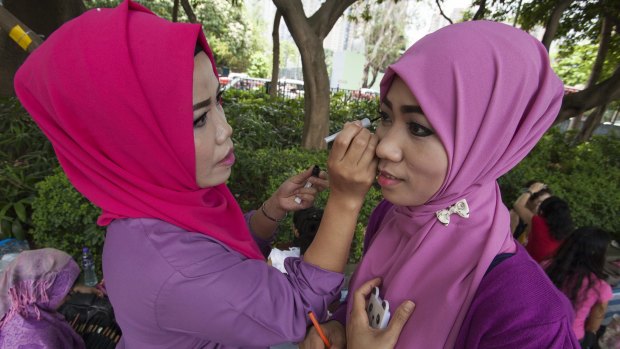Nurjanah, who works as a maid in Hong Kong, helps a colleague with makeup on their day off.