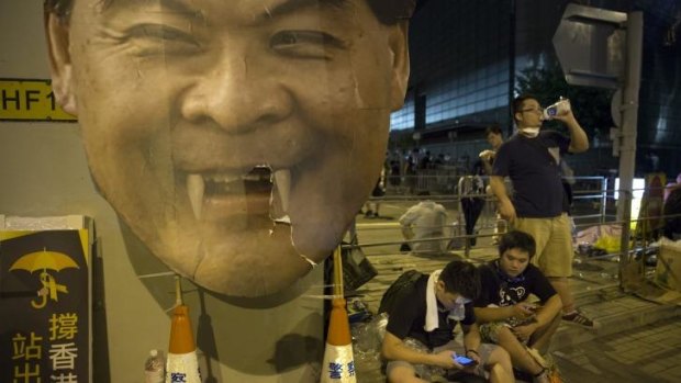 Protesters gather in the streets outside the Hong Kong Government Complex next to a cardboard poster of Hong Kong's chief executive C.Y.Leung.