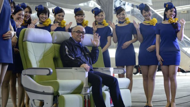 Shinichi Nishikubo, president of Skymark Airlines, poses for a photograph with members of the company's cabin crew.